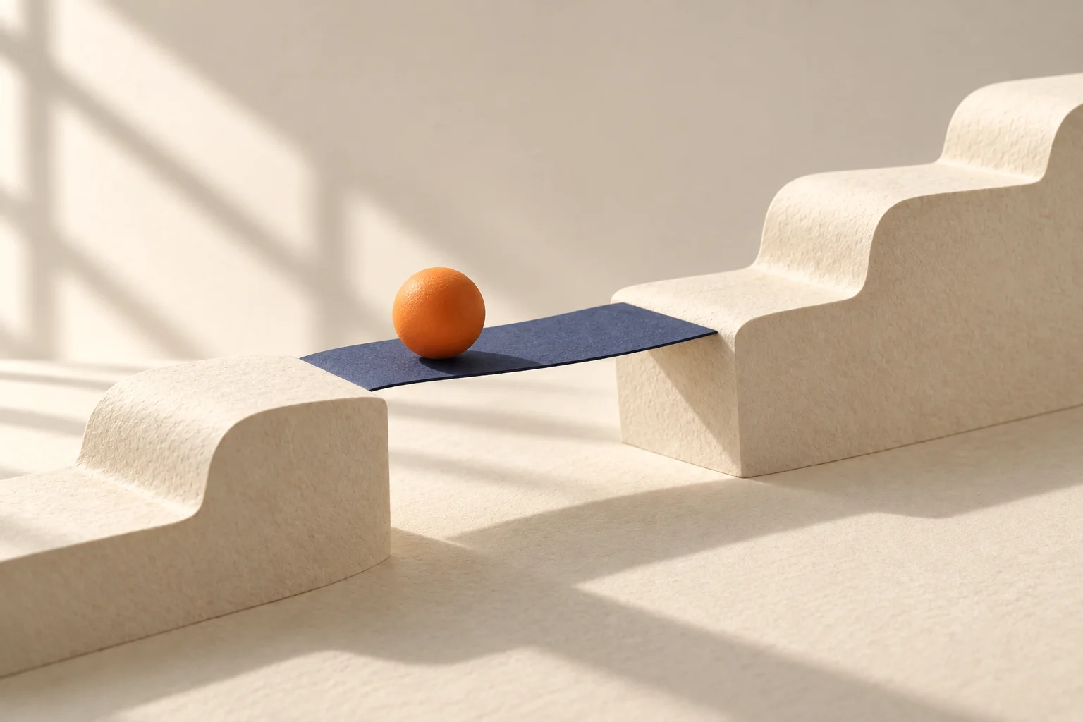 A navy paper bridge closes a gap in a cream paper path for an orange sphere.