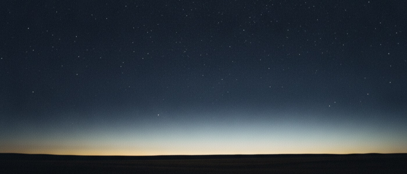Open ground under a full field of stars, first light along the horizon